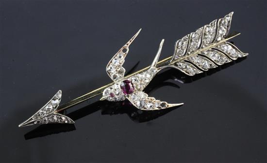 A mid 20th century gold, ruby and diamond set swallow and arrow brooch, 2.5in.